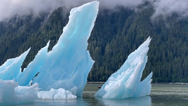 2021 - Tourists on an inflatable boat pass an iceberg in Alaska's LaConte Bay.
