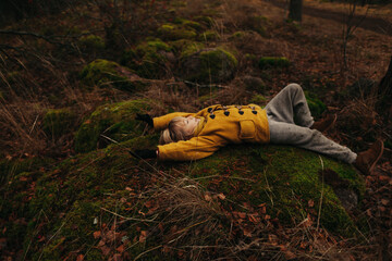 Little Child in the Woods Lying on a Mossy Stones 