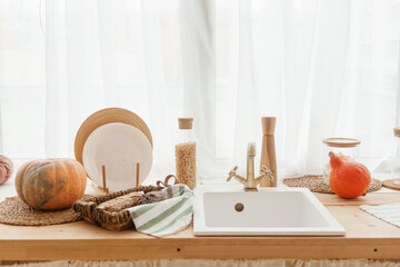 Kitchen countertop by the window in a bright room. Orange pumpkins, bread and pasta on the...