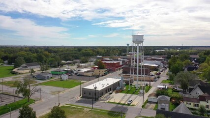 Aerial establishing shot over main street small town USA with water tower and freight train passing background.
