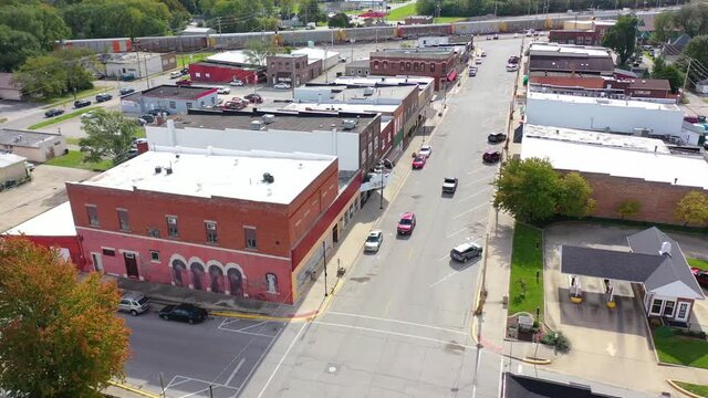 Aerial establishing shot over main street small town USA with water tower and freight train passing background.