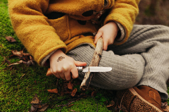 Hands of a Child Cutting Wooden Stick With a Knife