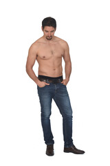 man shirtless and with blue jeans  looking down on white background