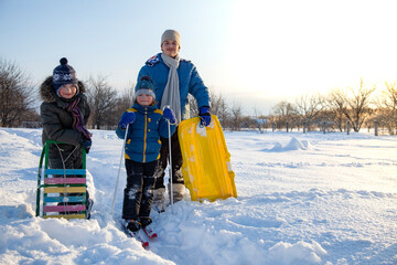 Three happy boys on sled and Skis in winter forest outdoors. Children active game