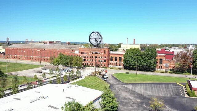 Aerial of a large old clock on the facade of an old abandoned vacant American factory near Jeffersonville, Indiana.