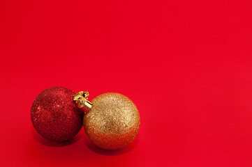 two shiny Christmas balls of red and gold colors on a red background