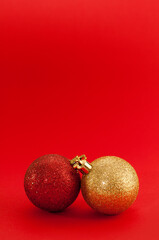 two shiny Christmas balls of red and gold colors on a red background