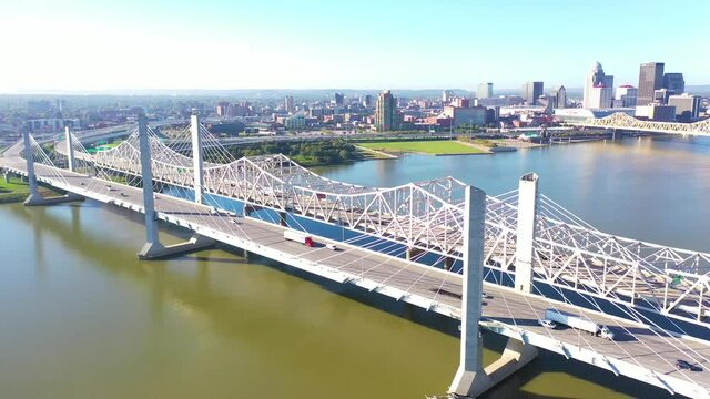 Aerial over Ohio River bridges with the Louisville, Kentucky downtown skyline distant suggests infrastructure.