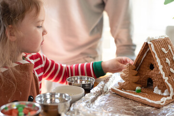 Little girl assembling a gingerbread house