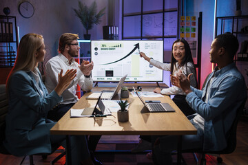 Asian woman presenting financial report of worldwide economy on big monitor during meeting with...