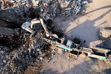 Excavator at landfill the load concrete waste in a mobile jaw crusher machine. Disposal of...