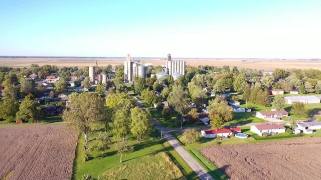 Aerial establishing shot over a small farming town USA with water tower and grain silo.