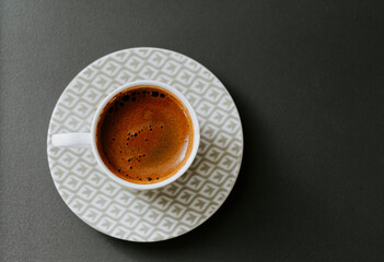 Turkish coffee in a white patterned cup with black background