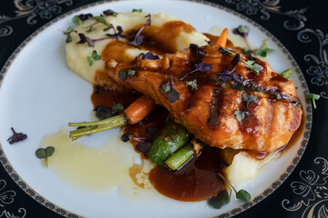 A dish of salmon with teriyaki sauce, mash potato and asparagus