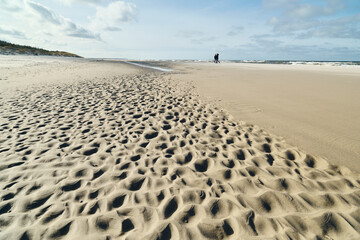 Zimowy spacer brzegiem Bałtyku. Chłodna tonacja, pomarszczona powierzchnia piaszczystej plaży,...
