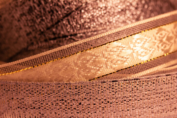 Macro abstract texture background of fabric ribbon in a shimmering shade of salmon pink
