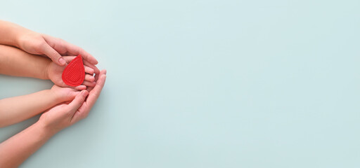 World hemophilia day. Hands of the mother and baby hold drop of blood on a blue background. Concept...