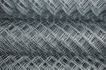Metal mesh netting rolled into rolls. Rolled chain-link fence.