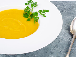 White plate with thick pumpkin cream soup. Studio Photo.