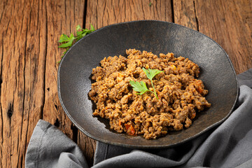 Ground beef in dark plate on the table.