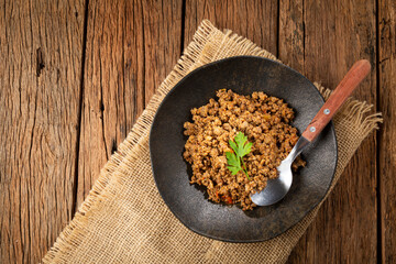 Ground beef in dark plate on the table.