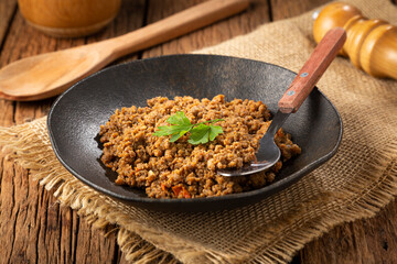 Ground beef in dark plate on the table.