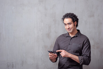 man in shirt holding mobile phone and looking at camera