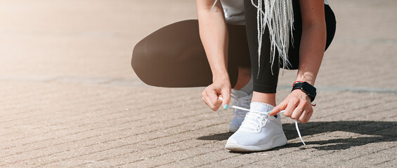  Woman tying running shoes in urban park. Horizontal sport poster, greeting cards, headers, website  and app