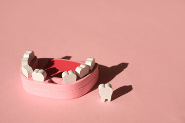 A model of a fake jaw with a lost front baby tooth on a pink background. Dental implantation. Tooth...