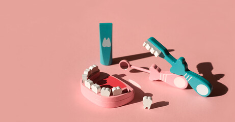 Wooden model of a jaw with a lost molar tooth and tools for daily dental care, examination and prevention of caries on a pink background. Dental concept banner. International dentists day
