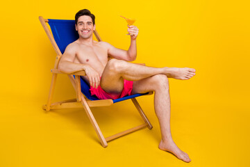 Full size profile side photo of young man happy smile sit chair enjoy cocktail vacation isolated over yellow color background - obrazy, fototapety, plakaty