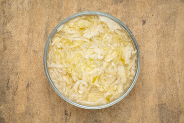 glass bowl of sauerkraut against  bark textured paper background, prebiotics concept - fermented food good for gut health