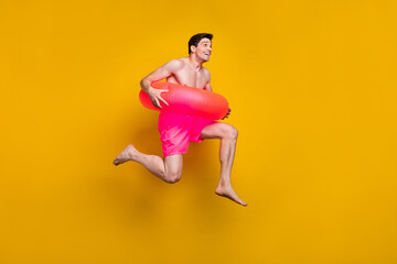 Fototapeta na wymiar Full length profile photo of cool young guy jump wear buoy pink shorts isolated on yellow background