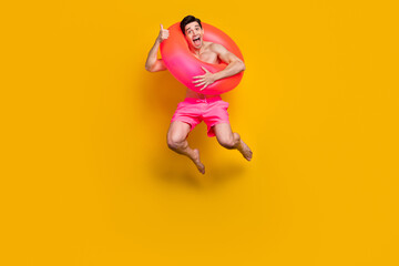 Fototapeta na wymiar Full body photo of young excited man happy positive smile trip resort bathing circle isolated over yellow color background