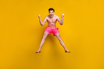 Fototapeta na wymiar Full length photo of hooray young guy jump wear pink shorts isolated on yellow background