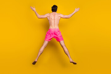 Fototapeta na wymiar Full body back rear view photo of young man jump up swimwear vacation isolated over yellow color background