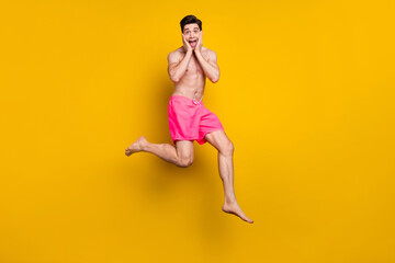 Full size photo of impressed young guy jump wear pink shorts isolated on yellow background