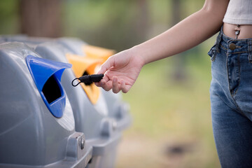 Close-up of a hand, mask and trash bin at outdoors. Girl in the park throws a medical mask into the bin