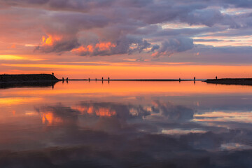 Reflection of clouds and sky in the calm river, sunset in the calm lake with silhouette of boat and fishermen, sandy coast in the bank of big river, Fishing by traditional methods in beautiful lake.