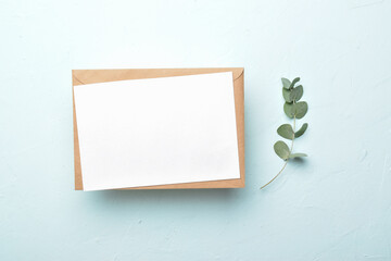 Minimalistic layout of a letter with an envelope on a blue background with eucalyptus.