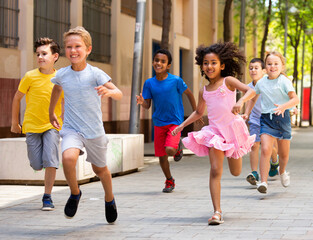 Obraz premium Group of joyful children running down the summer city street