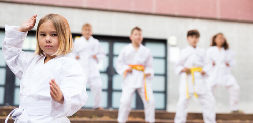 Fototapeta na wymiar Portrait of european preteen girl practicing karate on a street near school on sunny day