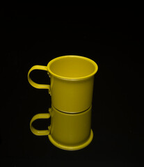 small yellow cup on a mirror and black background