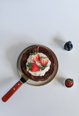 Flourless chocolate cake with whipping cream, strawberry and blueberry on white background. Homemade cake concept.