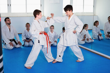 Pair of boys fighting in sparring to use new moves at karate class