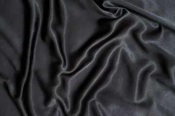 Obraz premium Black wavy silk background. Satin fabric texture. Dark elegant rich backdrop. Delicate design. Shine decoration christmas material. Tender art drape. Beautiful romantic textile