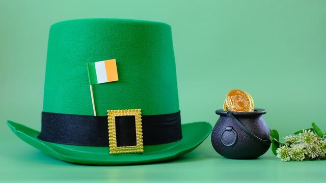 Patrick Day.Green leprechaun hat, flag of Ireland, bowler hat with gold coins, bunch of clovers on a green background. Saint Patrick holiday. St patricks day background. 4k footage