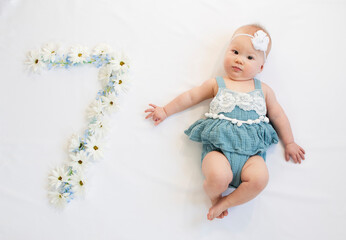 Little newborn baby girl in a blue dress. 7 month old baby