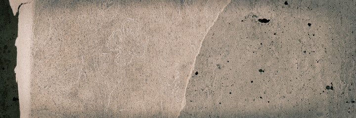 Torn old faded paper wallpaper with a retro pattern. Tattered scraps of paper on a concrete wall. Vintage texture for background and design. Closeup view with copy space.