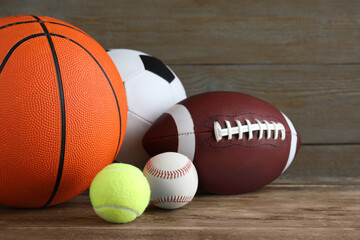 Set of different sport balls on wooden table, closeup